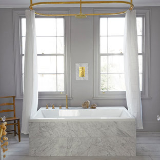 Cette photo montre une salle de bain scandinave avec une baignoire posée, un carrelage blanc, un mur gris, un combiné douche/baignoire et un sol en bois peint.