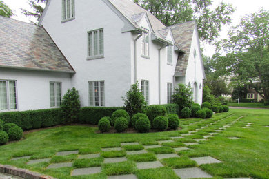 Photo of a large traditional three-storey stucco white house exterior in New York with a gable roof and a tile roof.
