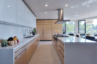 Photo of a mid-sized contemporary kitchen in Los Angeles with with island, flat-panel cabinets, light wood cabinets, quartz benchtops, beige splashback, stone slab splashback, stainless steel appliances, a double-bowl sink and porcelain floors.