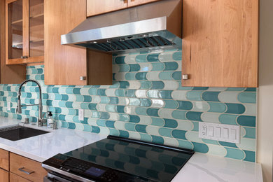 Kitchen - mid-sized 1960s l-shaped medium tone wood floor and brown floor kitchen idea in San Francisco with an undermount sink, flat-panel cabinets, medium tone wood cabinets, quartz countertops, multicolored backsplash, porcelain backsplash, stainless steel appliances, an island and white countertops