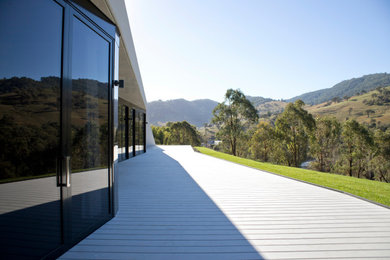 Cette image montre une façade de maison blanche design en béton de taille moyenne et de plain-pied avec un toit plat et un toit végétal.