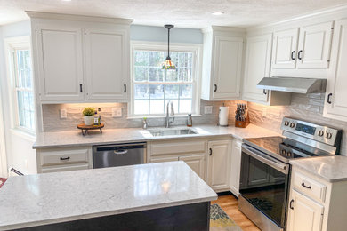 Eat-in kitchen - mid-sized transitional l-shaped medium tone wood floor and brown floor eat-in kitchen idea in Boston with an undermount sink, raised-panel cabinets, white cabinets, quartz countertops, gray backsplash, porcelain backsplash, stainless steel appliances, an island and gray countertops