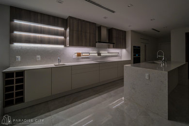 Design ideas for a large contemporary single-wall eat-in kitchen in Miami with an integrated sink, flat-panel cabinets, white cabinets, quartz benchtops, grey splashback, engineered quartz splashback, panelled appliances, porcelain floors, with island, grey floor and grey benchtop.