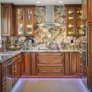 Inspiration pour une arrière-cuisine traditionnelle en U de taille moyenne avec un évier encastré, un placard avec porte à panneau surélevé, des portes de placard en bois brun, un plan de travail en granite, une crédence marron, une crédence en dalle de pierre, un électroménager en acier inoxydable, un sol en carrelage de porcelaine et aucun îlot.