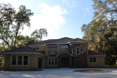 Photo of a large mediterranean two-storey yellow exterior in Orlando with mixed siding and a hip roof.