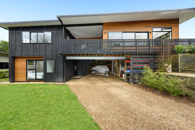 Photo of a contemporary two-storey black house exterior in Other with wood siding and a metal roof.