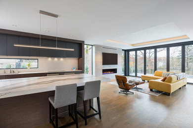 This is an example of a large contemporary open concept living room in Minneapolis with white walls, medium hardwood floors, a standard fireplace, a concrete fireplace surround, a wall-mounted tv, brown floor and recessed.