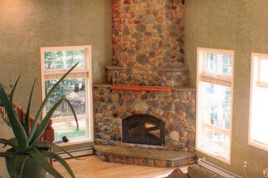 Living room - mid-sized light wood floor living room idea in New York with green walls, a corner fireplace and a stone fireplace