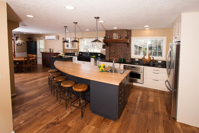 Inspiration for a country u-shaped eat-in kitchen in Boise with a drop-in sink, shaker cabinets, white cabinets, wood benchtops, red splashback, brick splashback, stainless steel appliances, dark hardwood floors, with island and brown floor.