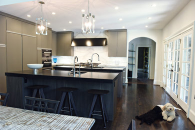 Open concept kitchen - mid-sized modern l-shaped dark wood floor and brown floor open concept kitchen idea in Atlanta with an undermount sink, flat-panel cabinets, brown cabinets, marble countertops, white backsplash, marble backsplash, stainless steel appliances and two islands