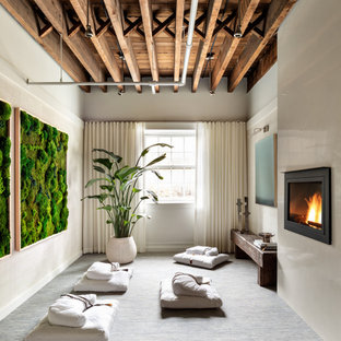 Mid-sized contemporary guest bedroom in New York with white walls, carpet, a hanging fireplace, a plaster fireplace surround and blue floor.