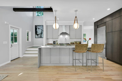 Mid-sized modern single-wall kitchen pantry in New York with an undermount sink, flat-panel cabinets, dark wood cabinets, quartz benchtops, white splashback, subway tile splashback, stainless steel appliances, light hardwood floors, with island, beige floor and white benchtop.