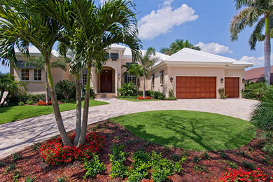 Large tropical one-storey stucco beige exterior in Miami with a gable roof.