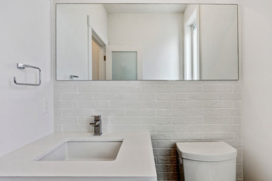 Example of a trendy white tile and stone tile ceramic tile powder room design in Calgary with flat-panel cabinets, dark wood cabinets, a two-piece toilet, white walls and an undermount sink