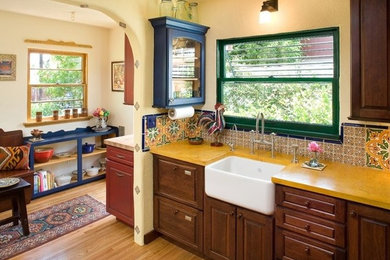 Eat-in kitchen - large eclectic u-shaped light wood floor eat-in kitchen idea in San Diego with a farmhouse sink, raised-panel cabinets, dark wood cabinets, quartzite countertops, yellow backsplash, ceramic backsplash and stainless steel appliances