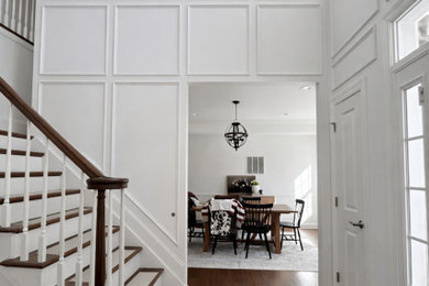 Entryway - large transitional light wood floor, brown floor, vaulted ceiling and wall paneling entryway idea in New York with white walls and a white front door