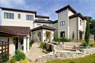 Large contemporary beige three-story stucco exterior home idea in Charlotte with a hip roof