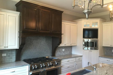 Inspiration for a large transitional l-shaped kitchen remodel in Chicago with an undermount sink, raised-panel cabinets, white cabinets, quartzite countertops, gray backsplash, subway tile backsplash, stainless steel appliances and an island