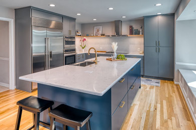 Inspiration for a mid-sized modern u-shaped light wood floor and beige floor eat-in kitchen remodel in DC Metro with a farmhouse sink, flat-panel cabinets, gray cabinets, quartz countertops, white backsplash, quartz backsplash, stainless steel appliances, an island and white countertops