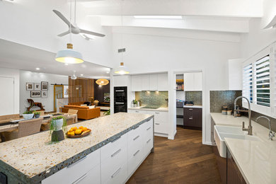 This is an example of an expansive contemporary l-shaped open plan kitchen in Other with a double-bowl sink, white cabinets, engineered stone countertops, metallic splashback, porcelain splashback, black appliances, medium hardwood flooring, an island, brown floors, beige worktops and exposed beams.
