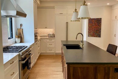 Example of a large transitional l-shaped light wood floor open concept kitchen design in Toronto with an undermount sink, recessed-panel cabinets, white cabinets, quartz countertops, paneled appliances and an island
