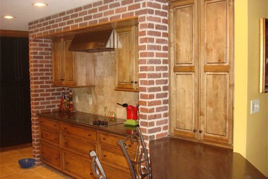 Inspiration for a farmhouse enclosed kitchen remodel in Other with flat-panel cabinets, light wood cabinets, solid surface countertops, black backsplash, stone tile backsplash and stainless steel appliances