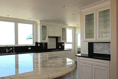 Inspiration for a large transitional single-wall dark wood floor and brown floor enclosed kitchen remodel in Los Angeles with recessed-panel cabinets, white cabinets, granite countertops, black backsplash, stone slab backsplash, an island and white countertops