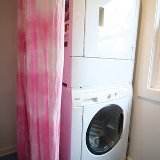 Inspiration for a medium sized contemporary galley separated utility room in Los Angeles with flat-panel cabinets, white cabinets, glass worktops, beige walls, ceramic flooring, a stacked washer and dryer and blue floors.