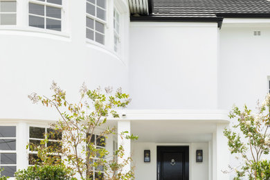 Large transitional two-storey white house exterior in Sydney with a gable roof, a tile roof and a black roof.