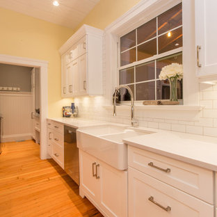 Пример оригинального дизайна: большая параллельная кухня в стиле кантри с кладовкой, раковиной в стиле кантри, фасадами в стиле шейкер, белыми фасадами, столешницей из кварцевого композита, белым фартуком, фартуком из плитки кабанчик, техникой из нержавеющей стали, паркетным полом среднего тона, островом и оранжевым полом