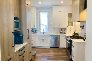 Small transitional l-shaped vinyl floor and brown floor eat-in kitchen photo in Other with a farmhouse sink, flat-panel cabinets, light wood cabinets, quartz countertops, white backsplash, ceramic backsplash, stainless steel appliances and white countertops