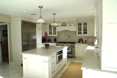 Photo of a mid-sized traditional u-shaped eat-in kitchen in New York with white floor, a farmhouse sink, beaded inset cabinets, white cabinets, white splashback, subway tile splashback, stainless steel appliances and with island.