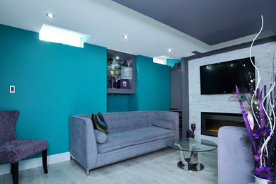 Basement - transitional look-out laminate floor and gray floor basement idea in Toronto with multicolored walls, a standard fireplace and a stone fireplace