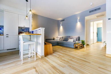 Esempio di un grande soggiorno mediterraneo aperto con pareti blu, TV a parete, angolo bar, parquet chiaro e pavimento marrone