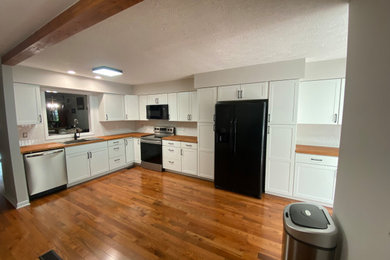 Kitchen pantry - modern l-shaped light wood floor and brown floor kitchen pantry idea in Other with a drop-in sink, shaker cabinets, white cabinets, wood countertops, white backsplash, ceramic backsplash and no island
