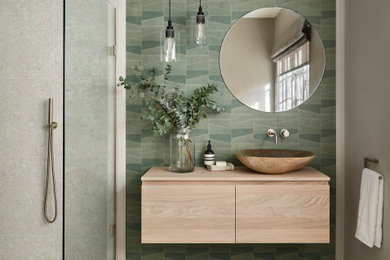 Inspiration for a medium sized contemporary bathroom in London with light wood cabinets, a wall mounted toilet, porcelain tiles, porcelain flooring, a vessel sink, wooden worktops, an open shower, feature lighting, a single sink, a floating vanity unit and wallpapered walls.