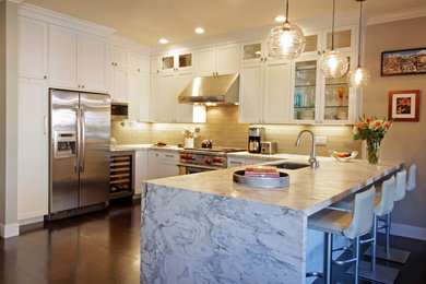 Example of a large u-shaped dark wood floor and brown floor eat-in kitchen design in San Francisco with marble countertops, glass tile backsplash, an undermount sink, shaker cabinets, white cabinets, beige backsplash, stainless steel appliances and a peninsula