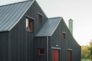 Ejemplo de fachada de casa bifamiliar negra y gris nórdica de tamaño medio de dos plantas con revestimiento de madera, tejado a dos aguas, tejado de metal y tablilla