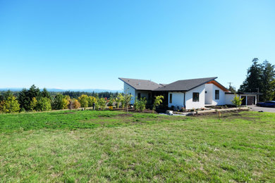 Example of a large minimalist white two-story stucco house exterior design in Portland with a shed roof, a shingle roof and a gray roof