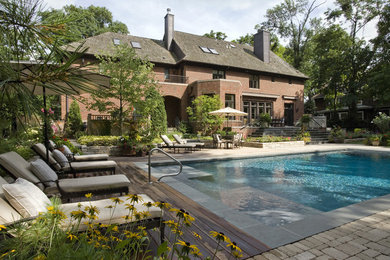 Photo of a traditional rectangular pool in Chicago with natural stone pavers.