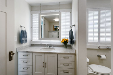 Inspiration for a mid-sized french country master white tile and ceramic tile porcelain tile, beige floor and single-sink bathroom remodel in Seattle with recessed-panel cabinets, white cabinets, yellow walls, an undermount sink, quartz countertops, a hinged shower door, a built-in vanity, a one-piece toilet and beige countertops