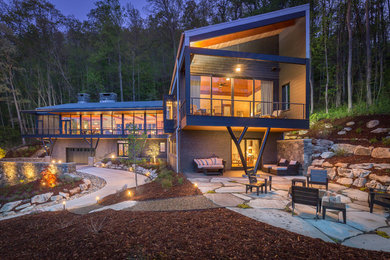 Example of a trendy two-story glass house exterior design in New York with a shed roof