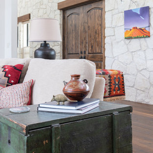 Mittelgroßes, Offenes Mediterranes Wohnzimmer mit weißer Wandfarbe, Kamin, Kaminsims aus Stein, braunem Boden und dunklem Holzboden in Austin