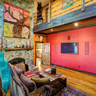 Offene Mediterrane Bibliothek mit roter Wandfarbe, hellem Holzboden, Kamin, Kaminsims aus Stein, Multimediawand und braunem Boden in Sonstige