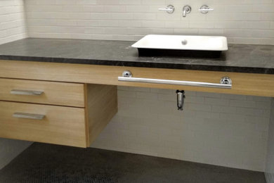 Bathroom - mid-sized contemporary white tile and subway tile bathroom idea in New York with flat-panel cabinets, light wood cabinets, a vessel sink, soapstone countertops and black countertops