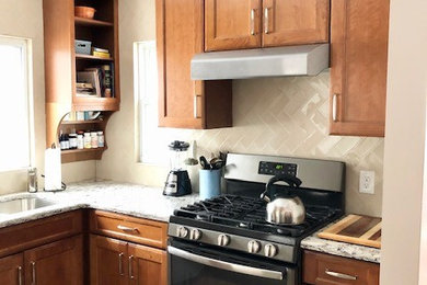 Example of a small classic u-shaped vinyl floor and beige floor eat-in kitchen design in Detroit with an undermount sink, recessed-panel cabinets, medium tone wood cabinets, quartz countertops, beige backsplash, glass tile backsplash, stainless steel appliances, no island and white countertops