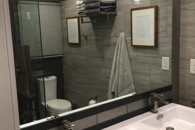 Inspiration for a small contemporary master gray tile and cement tile corner shower remodel in Indianapolis with a two-piece toilet, gray walls, an integrated sink and solid surface countertops