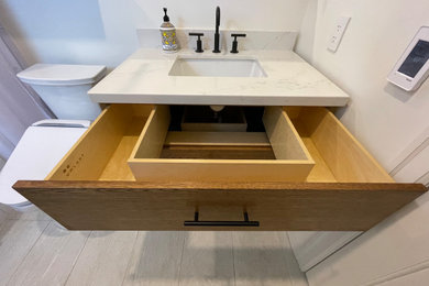 Inspiration for a mid-sized transitional white tile and subway tile porcelain tile, gray floor and single-sink bathroom remodel in San Francisco with furniture-like cabinets, medium tone wood cabinets, a bidet, white walls, an undermount sink, quartz countertops, white countertops, a niche and a freestanding vanity
