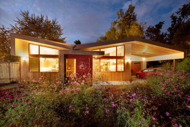 Photo of a contemporary one-storey red house exterior in Other with wood siding and a metal roof.