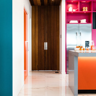 Cette image montre une grande arrière-cuisine parallèle design avec un évier encastré, des portes de placard oranges, un plan de travail en quartz, une crédence multicolore, une crédence en feuille de verre, un électroménager en acier inoxydable, un sol en carrelage de céramique, un îlot central, un sol blanc et un plan de travail gris.